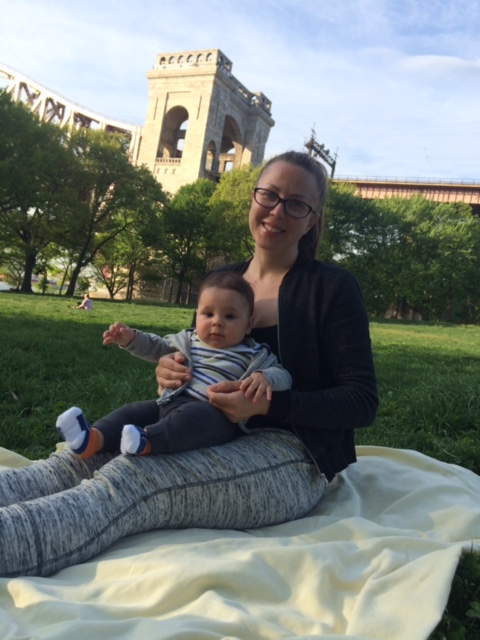 Kate Andreeva-Marino, client of Tribe of Mine, holding her baby on a slide in the park.