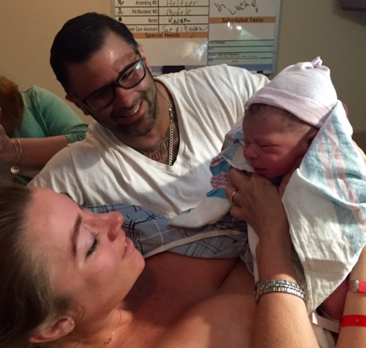 Kate Mangano, client of Tribe of Mine, in delivery room with newborn baby and husband